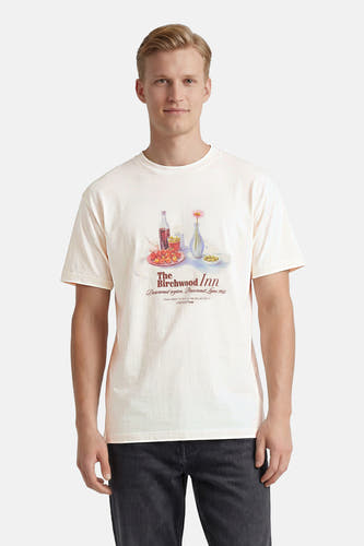 T-shirt blanc à manches courtes de ORIGINALS BY JACK & JONES avec une illustration de table colorée, porté par un homme en jean foncé.