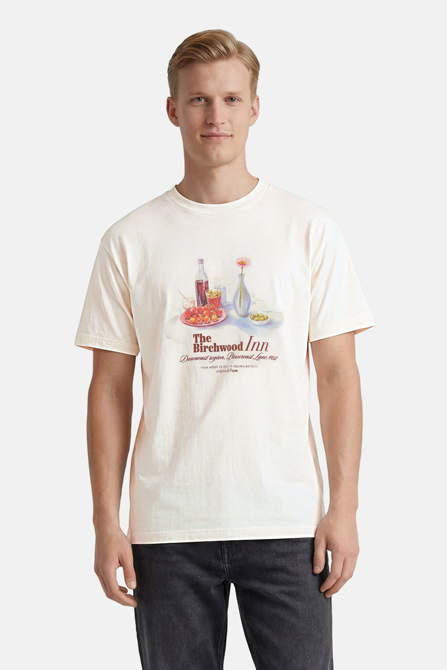 T-shirt blanc à manches courtes de ORIGINALS BY JACK & JONES avec une illustration de table colorée, porté par un homme en jean foncé.