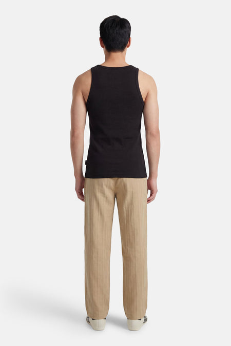 Zwart singlet van CORE BY JACK & JONES, met ribtextuur, gecombineerd met beige gestreepte pantalon en witte sneakers.