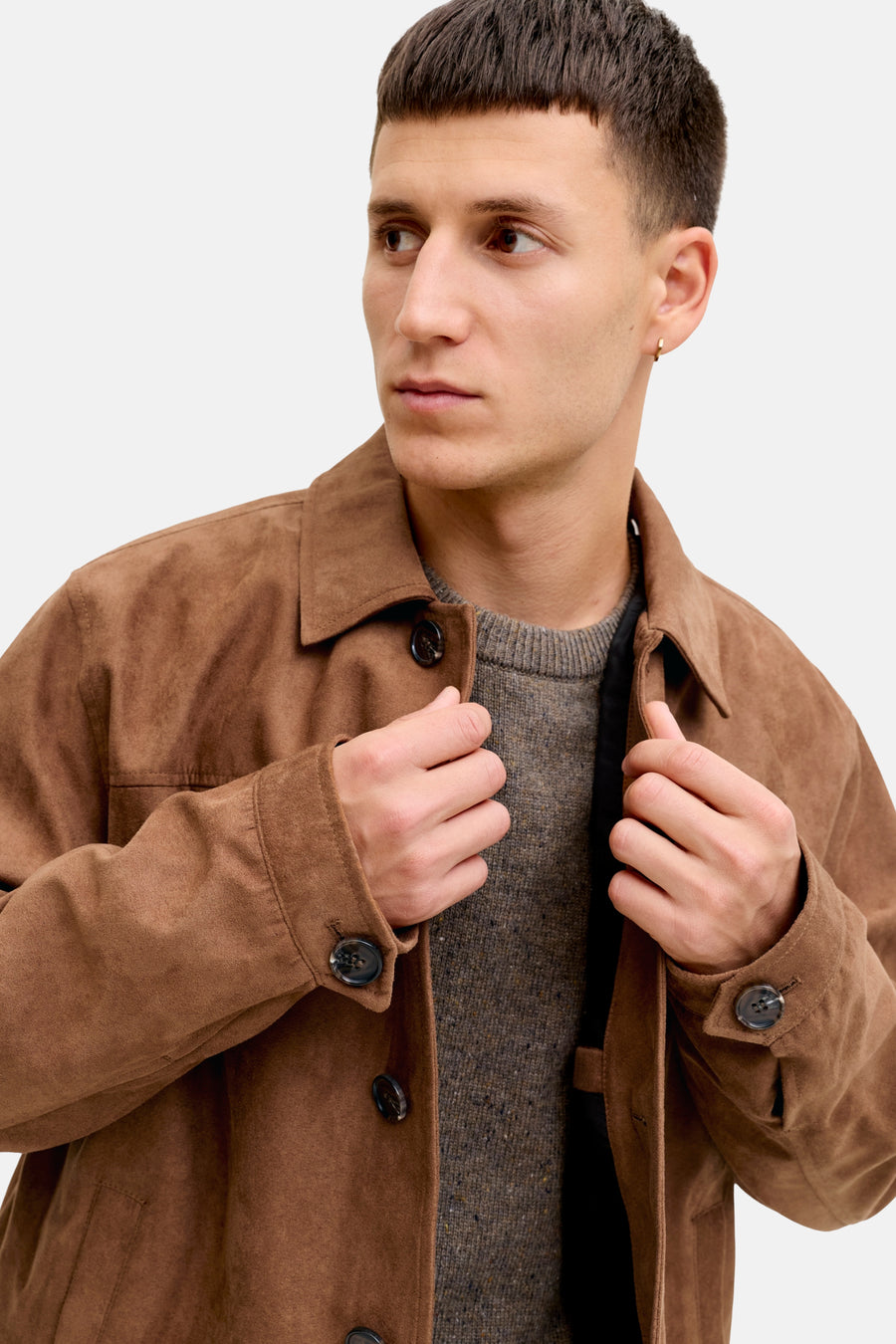 Man in bruine suède jas met grijze trui.