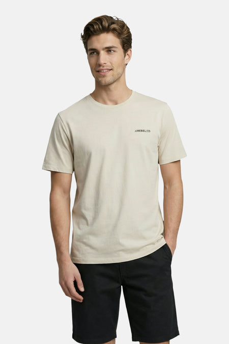 T-shirt beige de JJREBEL avec texte noir 'JJREBEL / ES' sur la poitrine, porté par un homme avec un short noir.