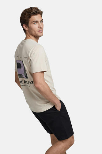 T-shirt beige de JJREBEL avec imprimé graphique violet et noir au dos, porté avec un short noir.