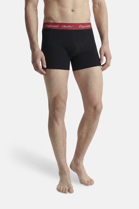 Zwarte boxershort van ACCESSORIES BY JACK & JONES met een rode tailleband met wit 'Originals Studio™ Originals' opschrift, gedragen door een man.