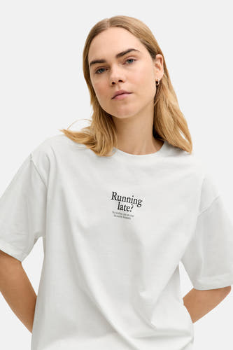 T-shirt blanc à manches courtes de JJXX, avec le texte "Running late?", porté par un mannequin blond.