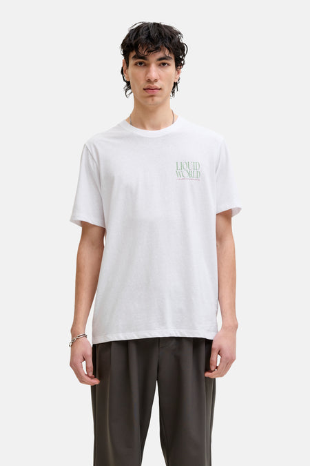 T-shirt blanc de ORIGINALS BY JACK & JONES, avec un petit imprimé texte, combiné avec un pantalon foncé et des baskets marron.