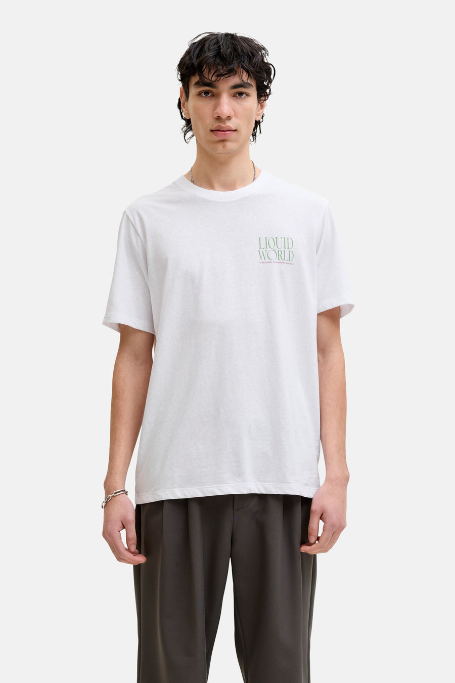T-shirt blanc de ORIGINALS BY JACK & JONES, avec un petit imprimé texte, combiné avec un pantalon foncé et des baskets marron.
