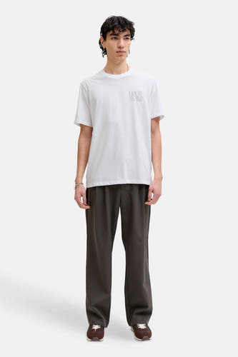 Wit T-shirt van ORIGINALS BY JACK & JONES, met een kleine tekstprint, gecombineerd met een donkere pantalon en bruine sneakers.