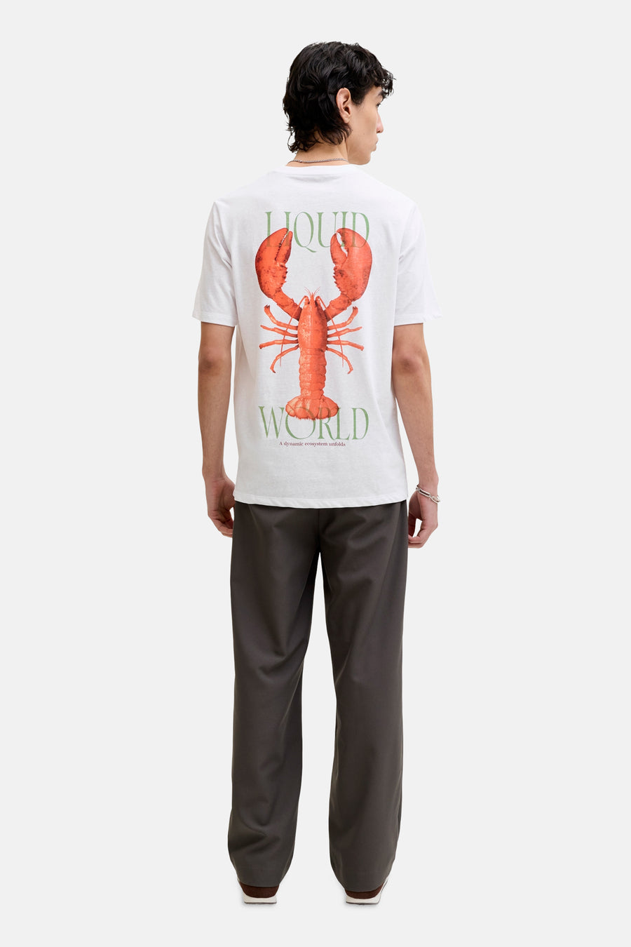 T-shirt blanc de ORIGINALS BY JACK & JONES, avec imprimé homard et texte vert au dos, porté avec un pantalon gris.