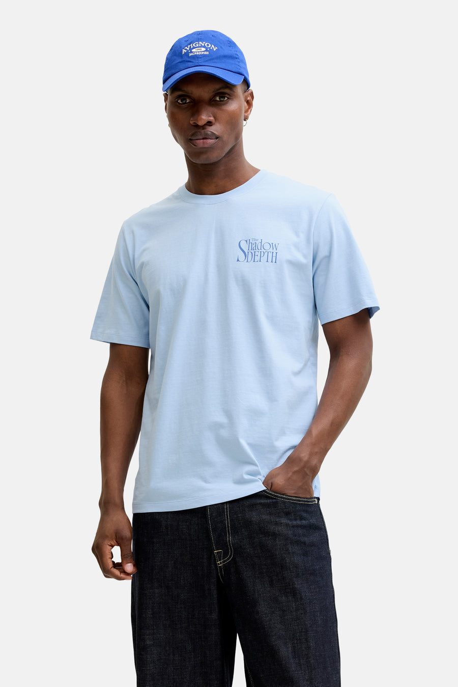 T-shirt bleu de ORIGINALS BY JACK & JONES, à manches courtes et avec un imprimé texte, combiné avec une casquette bleue et un jean foncé.