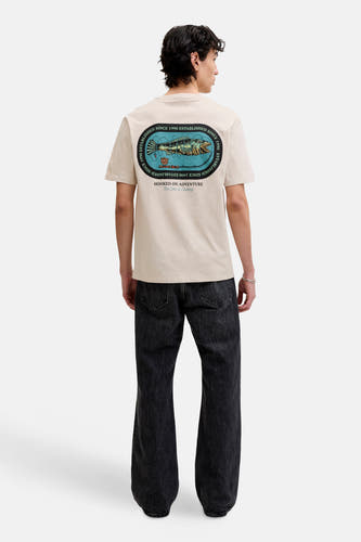 T-shirt beige de ORIGINALS BY JACK & JONES, avec un imprimé graphique au dos et porté avec un jean noir.