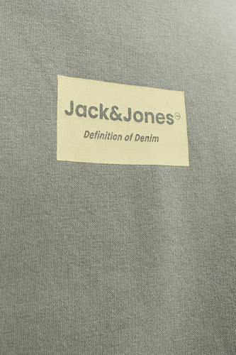 Pull vert de CORE BY JACK & JONES, avec une étiquette avec le logo de la marque, sur une texture finement tricotée.