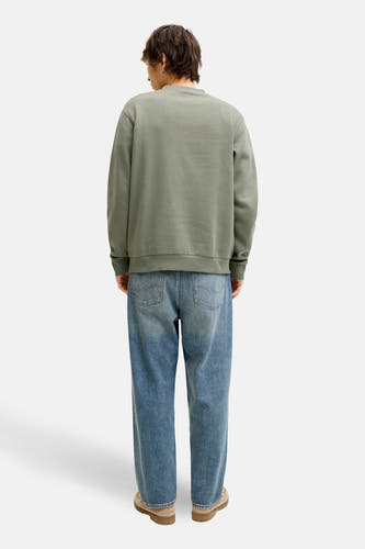 Pull vert de CORE BY JACK & JONES, à manches longues, porté avec un jean bleu et des chaussures en daim.