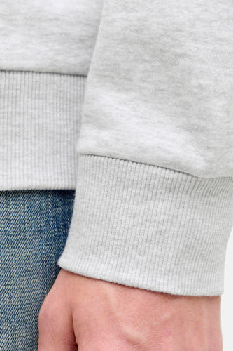 Pull gris à col rond de CORE BY JACK & JONES, avec détails côtelés et denim partiellement visible.