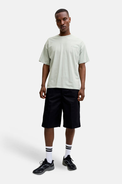 Groen T-shirt met korte mouwen van CORE BY JACK & JONES met lichtgrijze grafische print op de borst, gestyled met zwarte shorts, witte sokken met zwarte strepen en sneakers.
