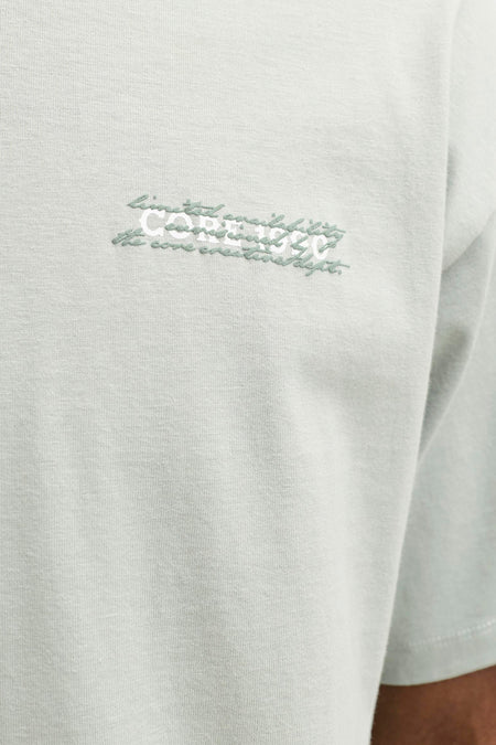 T-shirt à manches courtes vert de CORE BY JACK & JONES, gros plan sur la poitrine avec inscription brodée blanche et verte.