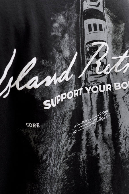 T-shirt noir à manches courtes de CORE BY JACK & JONES avec un imprimé graphique blanc d'un bateau et de textes, gros plan.