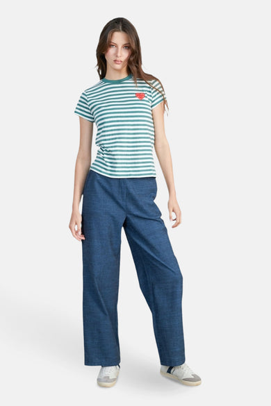 T-shirt rayé vert avec des manches courtes de 24 couleurs, avec un petit cœur rouge et associé à des pantalons bleus et des baskets.