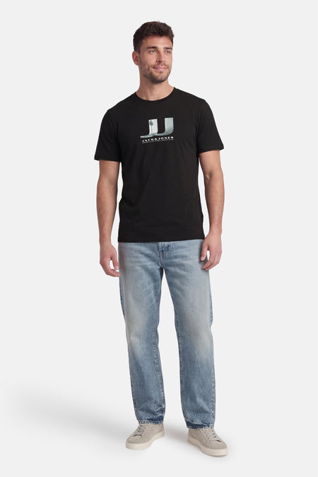 T-shirt noir à manches courtes de CORE by JACK & JONES, avec imprimé graphique et porté avec un jean et des baskets.