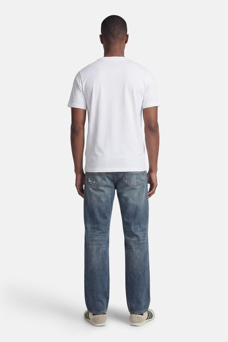 T-shirt blanc à manches courtes de CORE BY JACK & JONES, avec un motif uni et porté avec un jean bleu et des baskets.