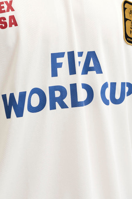 Polo blanche ORIGINALS BY JACK & JONES avec inscription bleue 'FIFA WORLD CUP', inscription rouge 'EX SA' et un écusson FIFA World Cup de couleur or.