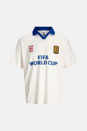 Polo blanc ORIGINALS BY JACK & JONES avec col bleu, texte rouge 'CAN MEX USA', écusson doré FIFA 26 et lettres bleues 'FIFA WORLD CUP'.
