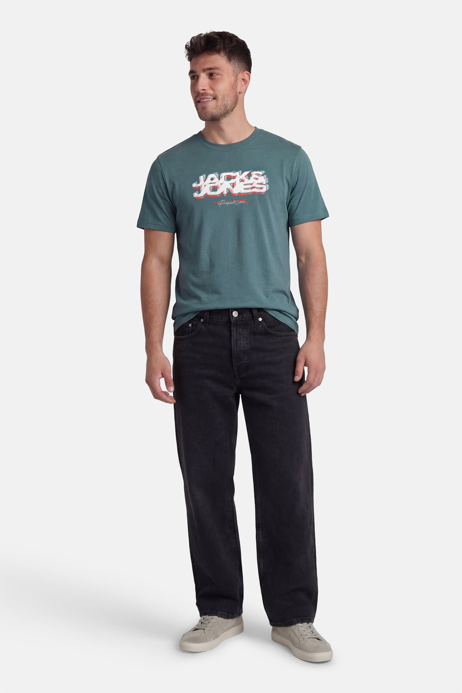Groen T-shirt met korte mouwen van CORE by JACK & JONES, met een bedrukte tekst, gedragen met zwarte jeans en grijze sneakers.
