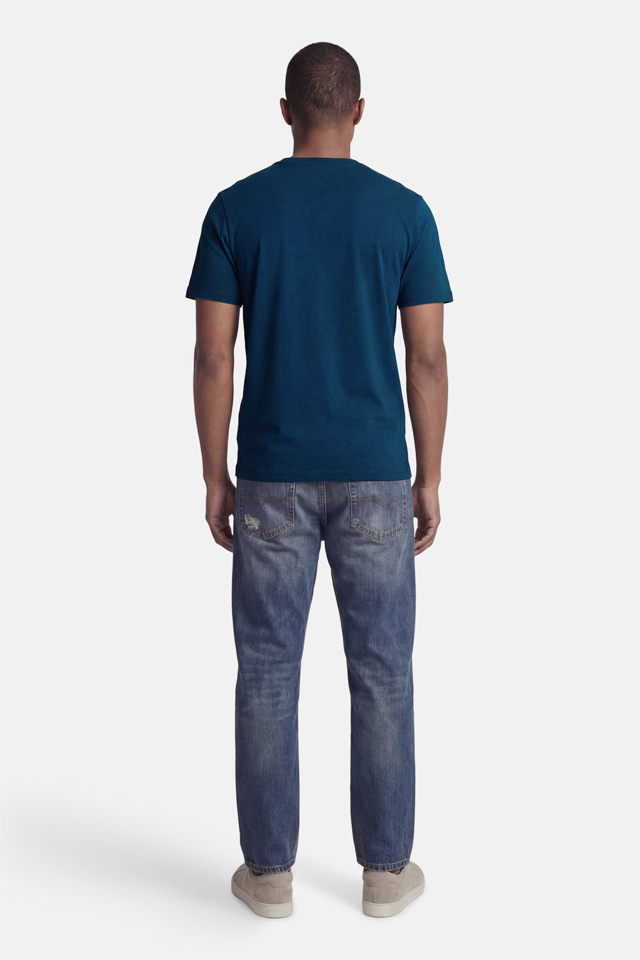 T-shirt bleu à manches courtes de CORE BY JACK & JONES, vu de dos, associé à un jean et des chaussures grises.