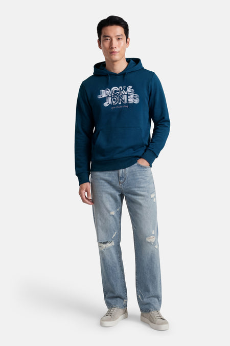 Sweatshirt à capuche bleu de CORE BY JACK & JONES, avec imprimé sur la poitrine, combiné avec un jean déchiré et des baskets.