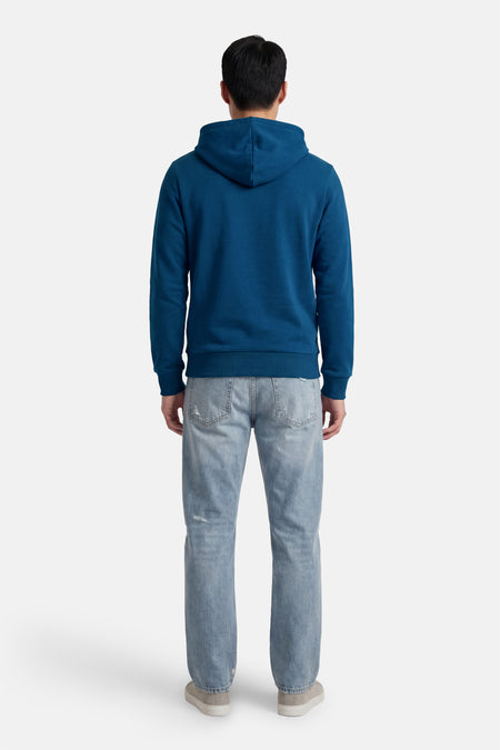 Blauwe sweater met kap van CORE BY JACK & JONES, gezien van achteren, met spijkerbroek en grijze schoenen.