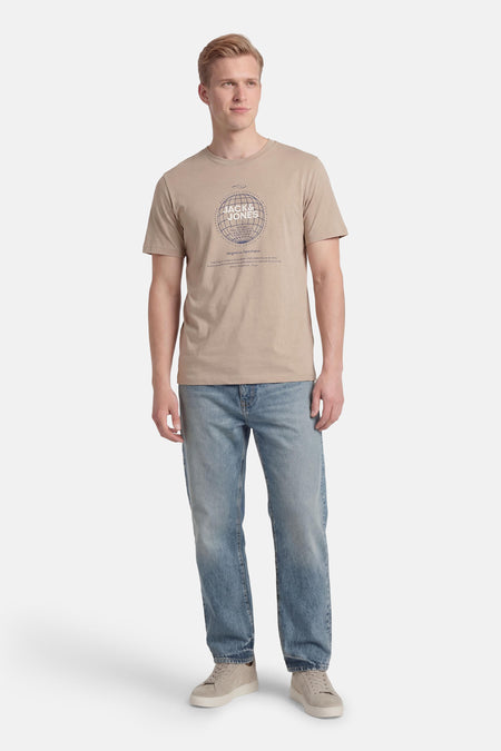 Beige T-shirt met korte mouwen van CORE by JACK & JONES, met een globe-achtige print, gecombineerd met jeans en suède schoenen.
