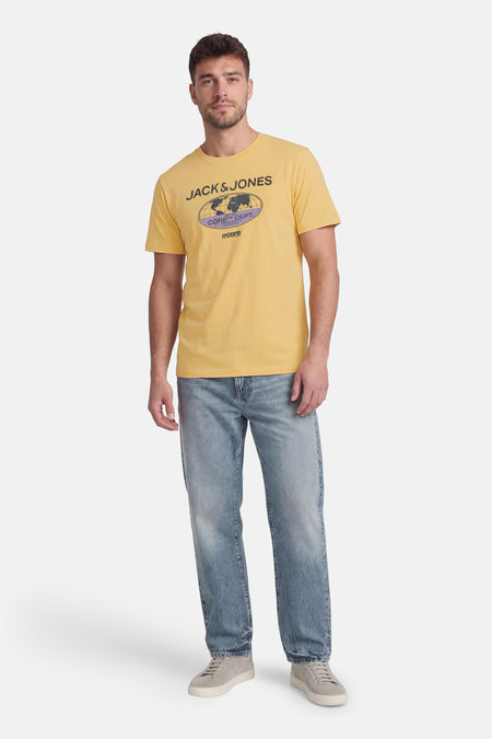 Geel T-shirt met korte mouwen van CORE BY JACK & JONES, met grafische print, gecombineerd met blauwe jeans en grijze sneakers.