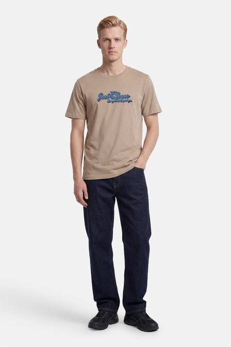 Beige T-shirt van ORIGINALS BY JACK & JONES met blauw 'Jack & Jones' logo op de borst, gedragen door een model.