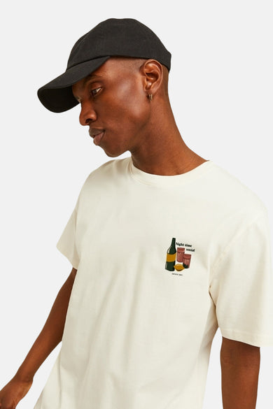 T-shirt écru à manches courtes d'ORIGINALS BY JACK & JONES, avec une impression graphique et porté avec un chapeau noir.