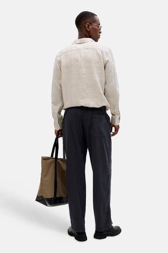 Pantalon de saison élastique noir pour homme de JACK & JONES JEANS INTELLIGENCE, avec texture légère et poche arrière, porté par un homme de dos.