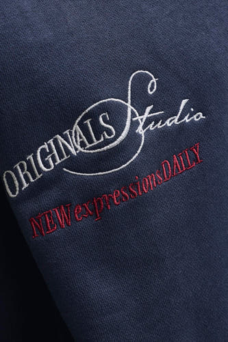 Pull bleu marine à col rond de ORIGINALS BY JACK & JONES, avec texte brodé blanc et rouge.