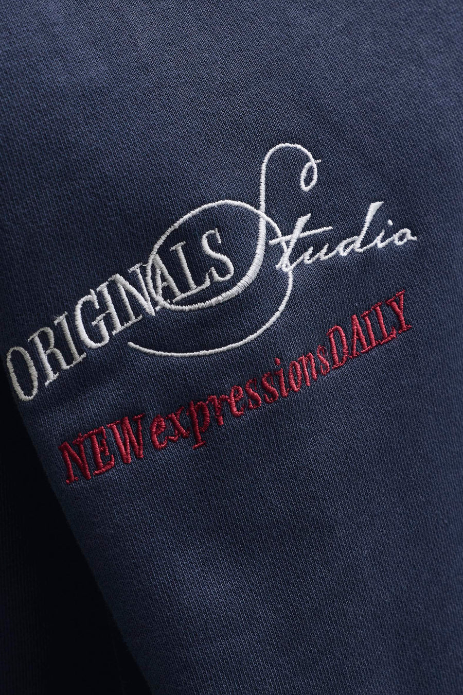 Pull bleu marine à col rond de ORIGINALS BY JACK & JONES, avec texte brodé blanc et rouge.