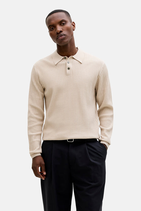 Polo beige côtelée de PREMIUM by JACK & JONES, portée sous une veste verte ouverte avec un pantalon noir et des mocassins.