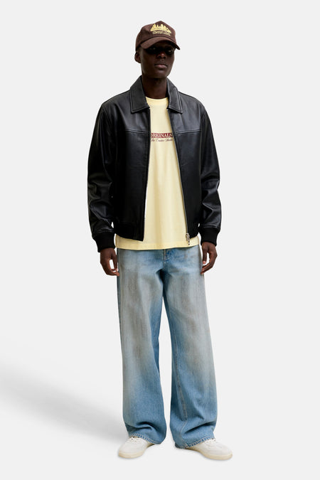 Geel T-shirt met korte mouwen van ORIGINALS BY JACK & JONES met grafische print, gedragen met een zwart leren jack en wijde spijkerbroek.