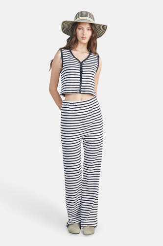 Wit gilet van 24 colours met zwarte strepen en knoopsluiting, gecombineerd met gestreepte broek en strohoed.
