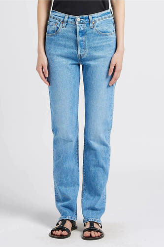 Jean droit bleu clair de Levi's, vu de derrière, associé à une hoodie crème et une beanie verte.