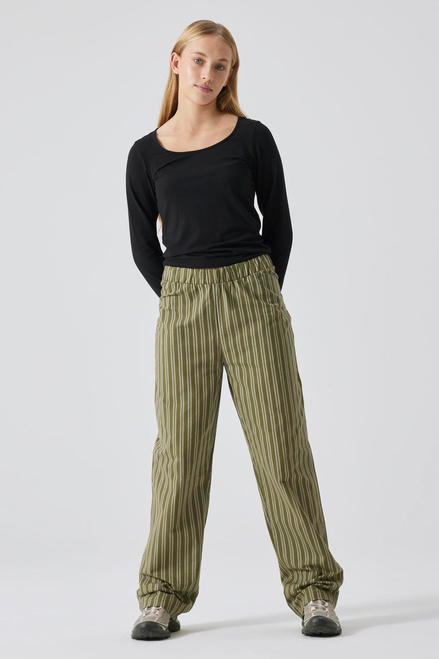Pull noir avec col rond de LMTD, porté avec un pantalon rayé vert olive.