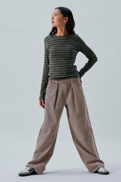 Pantalon brun de LMTD, avec plis et une large ceche, associé à un t-shirt rayé et des baskets.