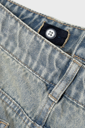 Close-up van spijkerbroek met verstelbare tailleband en knoop.