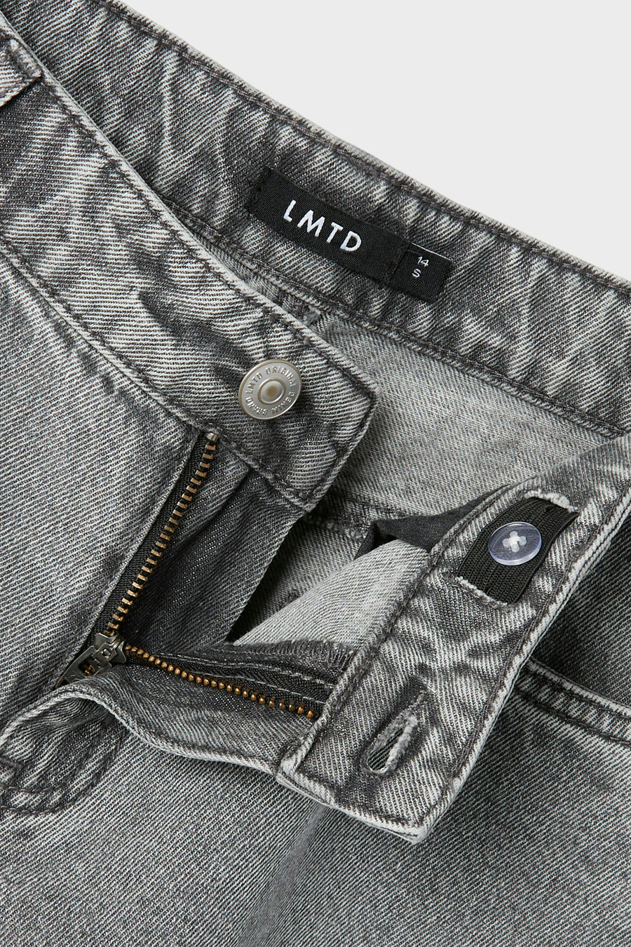 Grijze jeans met ritssluiting, knoop en merklabel.
