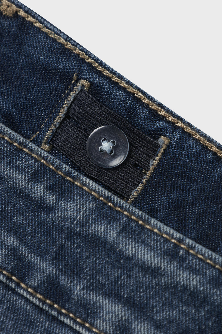 Jean en denim bleu marine large de LMTD, avec une ceinture ajustable et un détail de bouton, gros plan.
