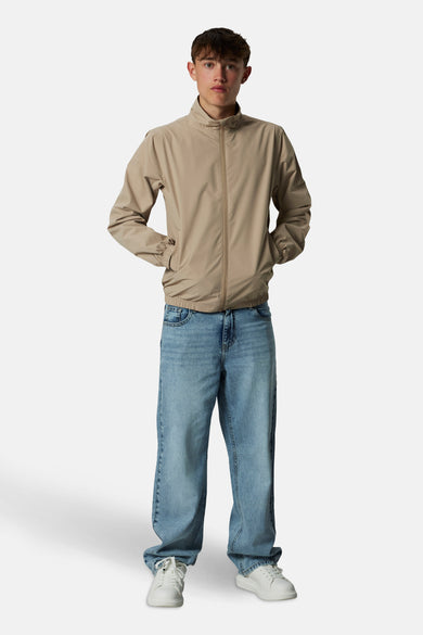 Jean bleu clair large de LMTD, associé à une veste beige et des baskets blanches.