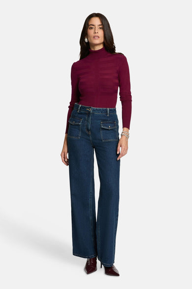 Paarse trui met rolkraag van Morgan De Toi, met horizontale strepen en gecombineerd met jeans met zakken en rode laarsjes.

