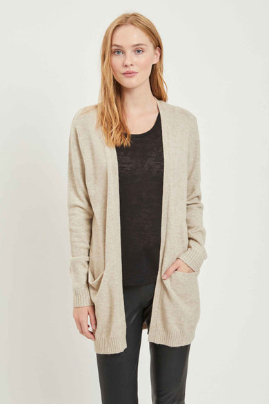 Veste beige de VILA, avec des poches et portée sur un t-shirt noir et un pantalon noir.
