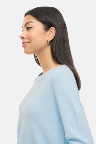 Sweat-shirt bleu decolleuré col V V V V, vu vu côté côté avec des boucles d'oreilles en argent.