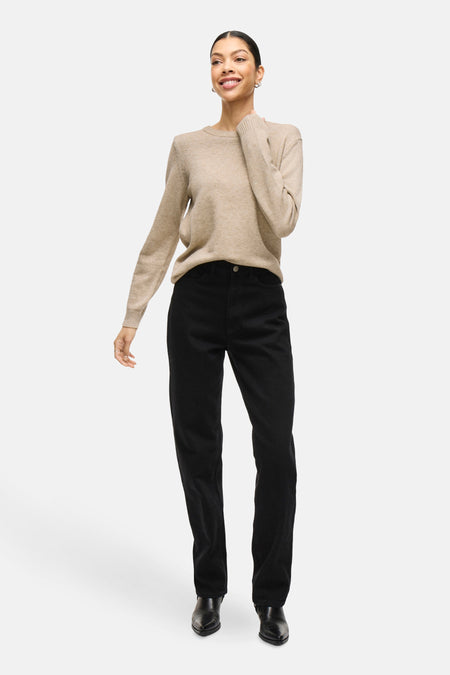 Pull beige à col rond de VILA, porté avec un pantalon noir et des chaussures noires.